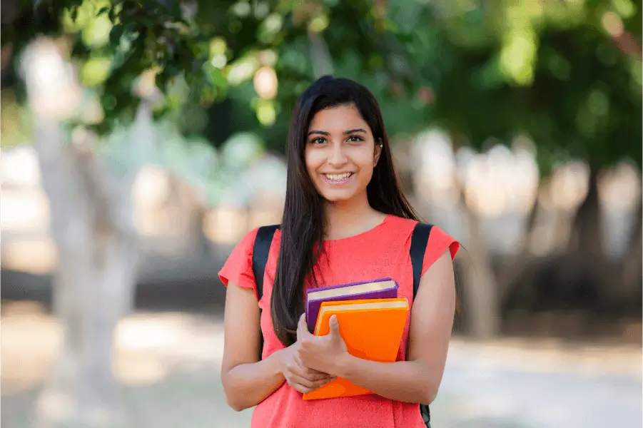 Image of a female student smiling and holding books