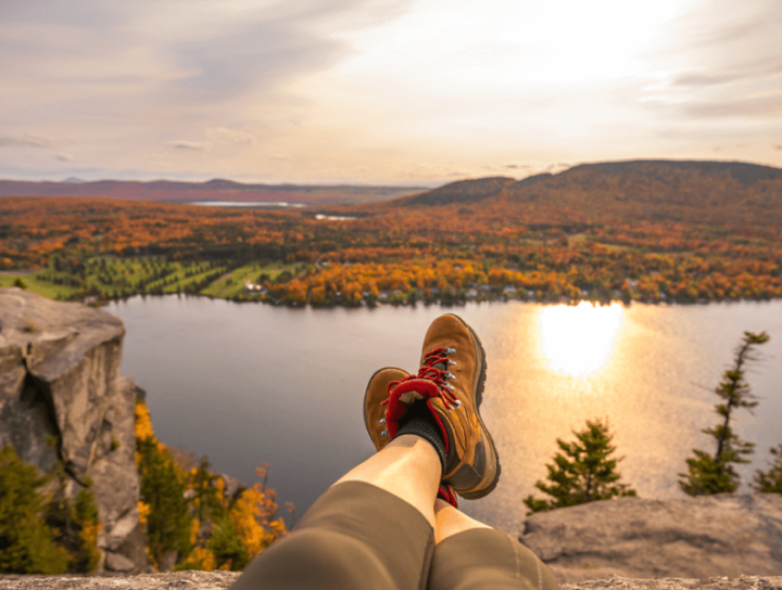 Image of a person's boots with river and mountains during fall