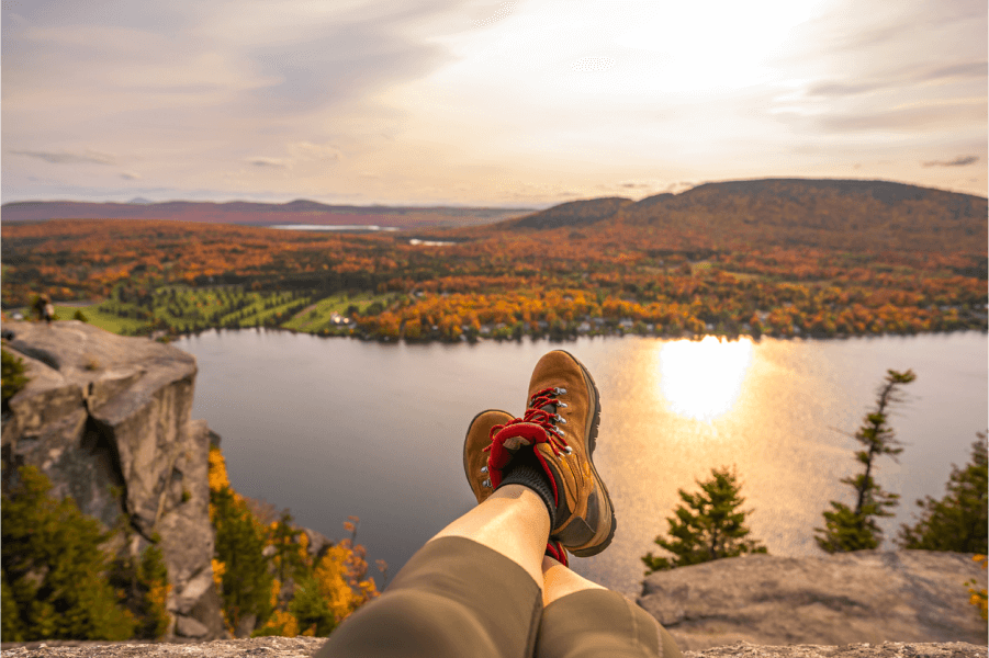 Image of a person's boots with river and mountains during fall
