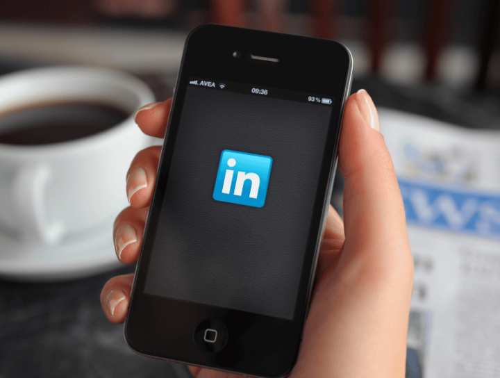 Image of a hand holding a phone with Linkedin Logo at the middle