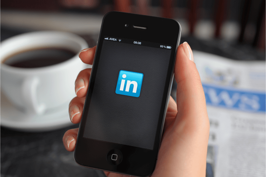 Image of a hand holding a phone with Linkedin Logo at the middle