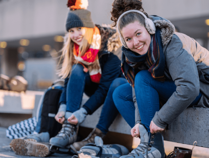 Image of two women strapping on ice skates