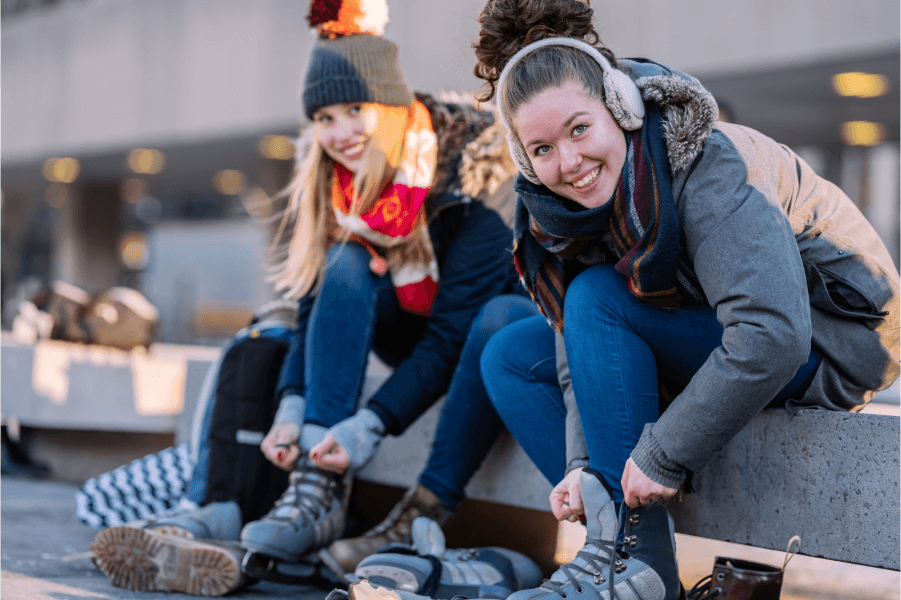 Image of two women strapping on ice skates