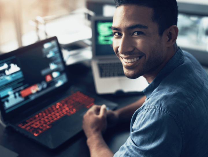 Image of a smiling man with laptops behind him