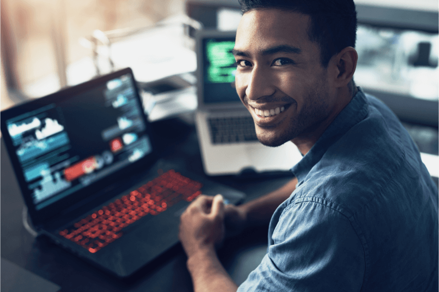 Image of a smiling man with laptops behind him